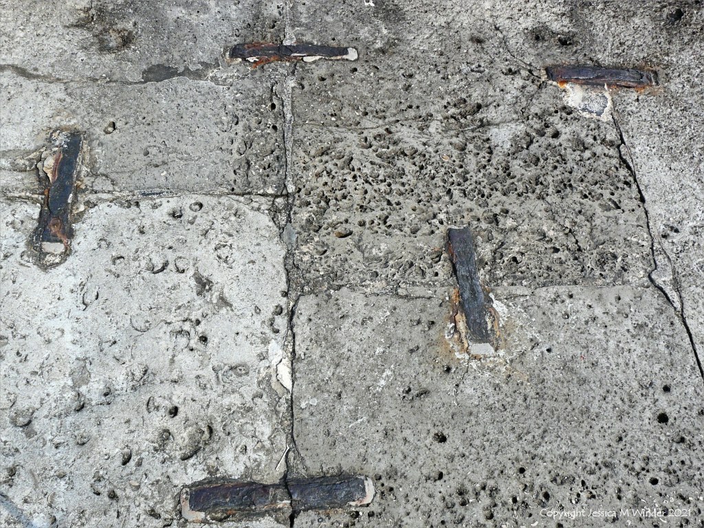Stone blocks in a sea wall with shaped holes left by erosion of shell fossils