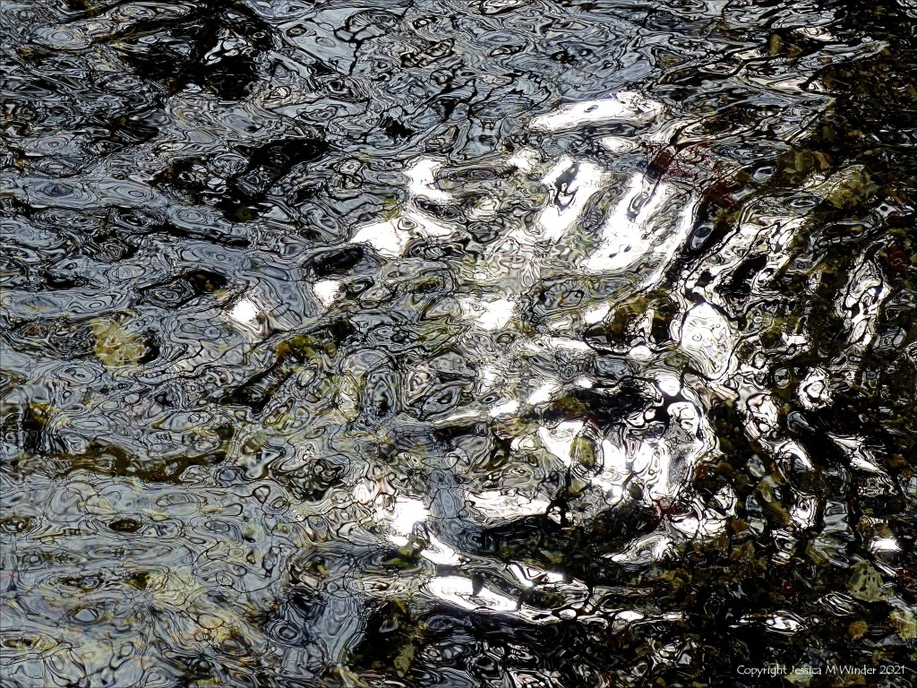 Detail of black and white dappled light reflection patterns on flowing river water