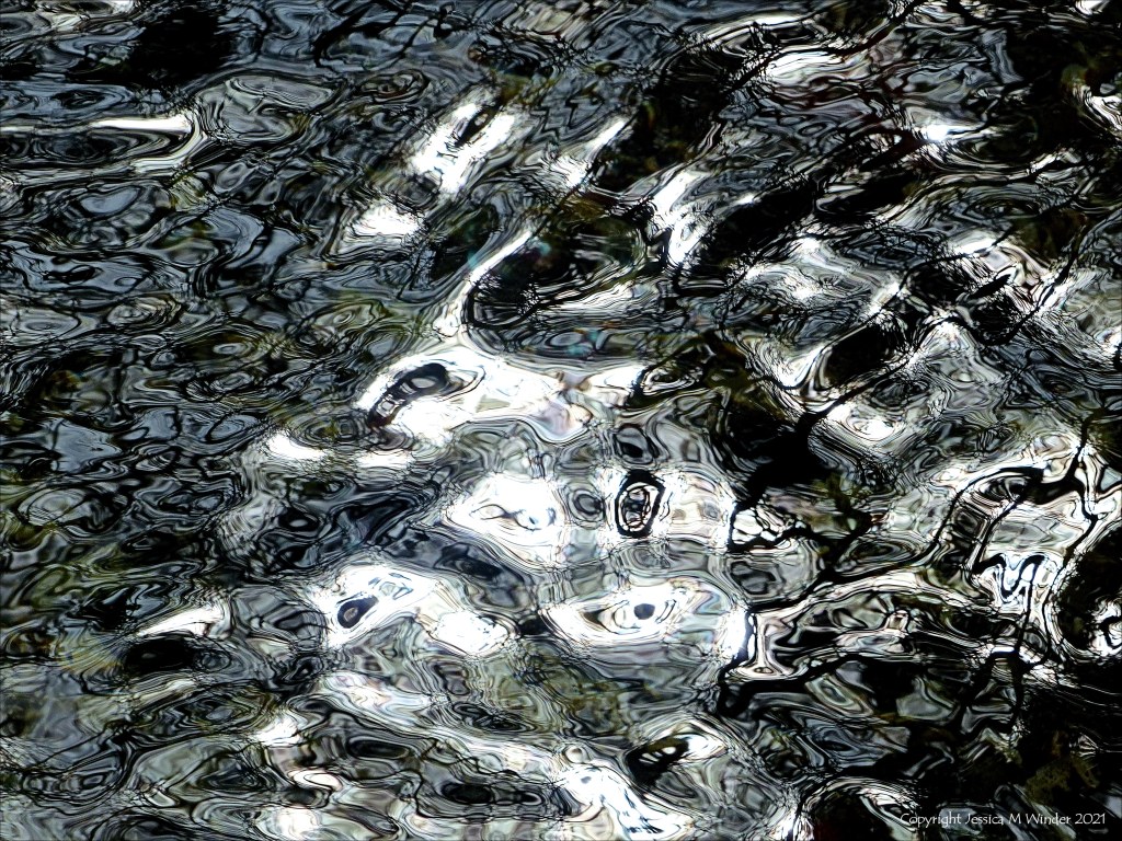 Detail of black and white dappled light reflection patterns on flowing river water