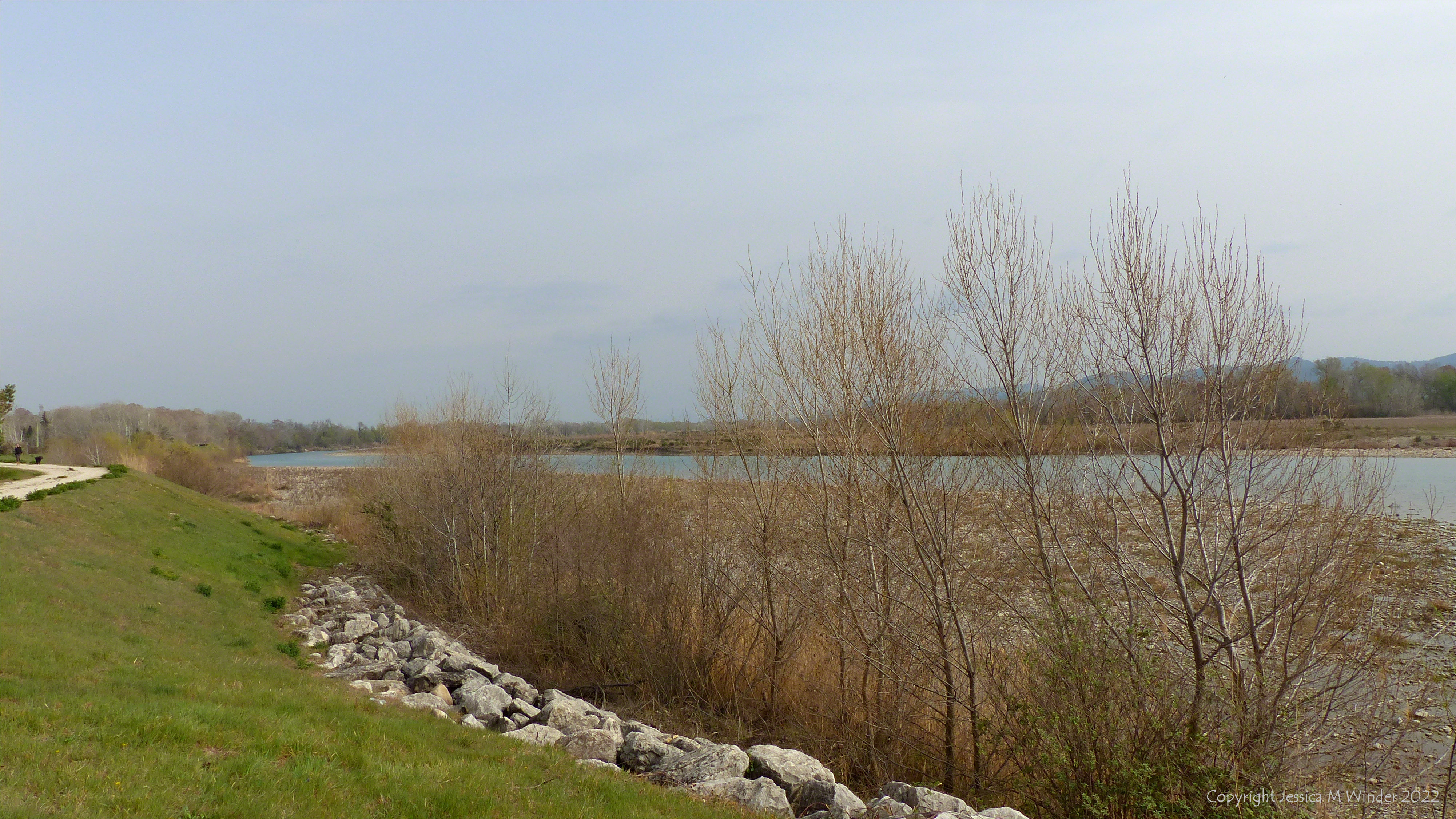 Large mature river with partially vegetated pebble banks and a man-made levee in Provence