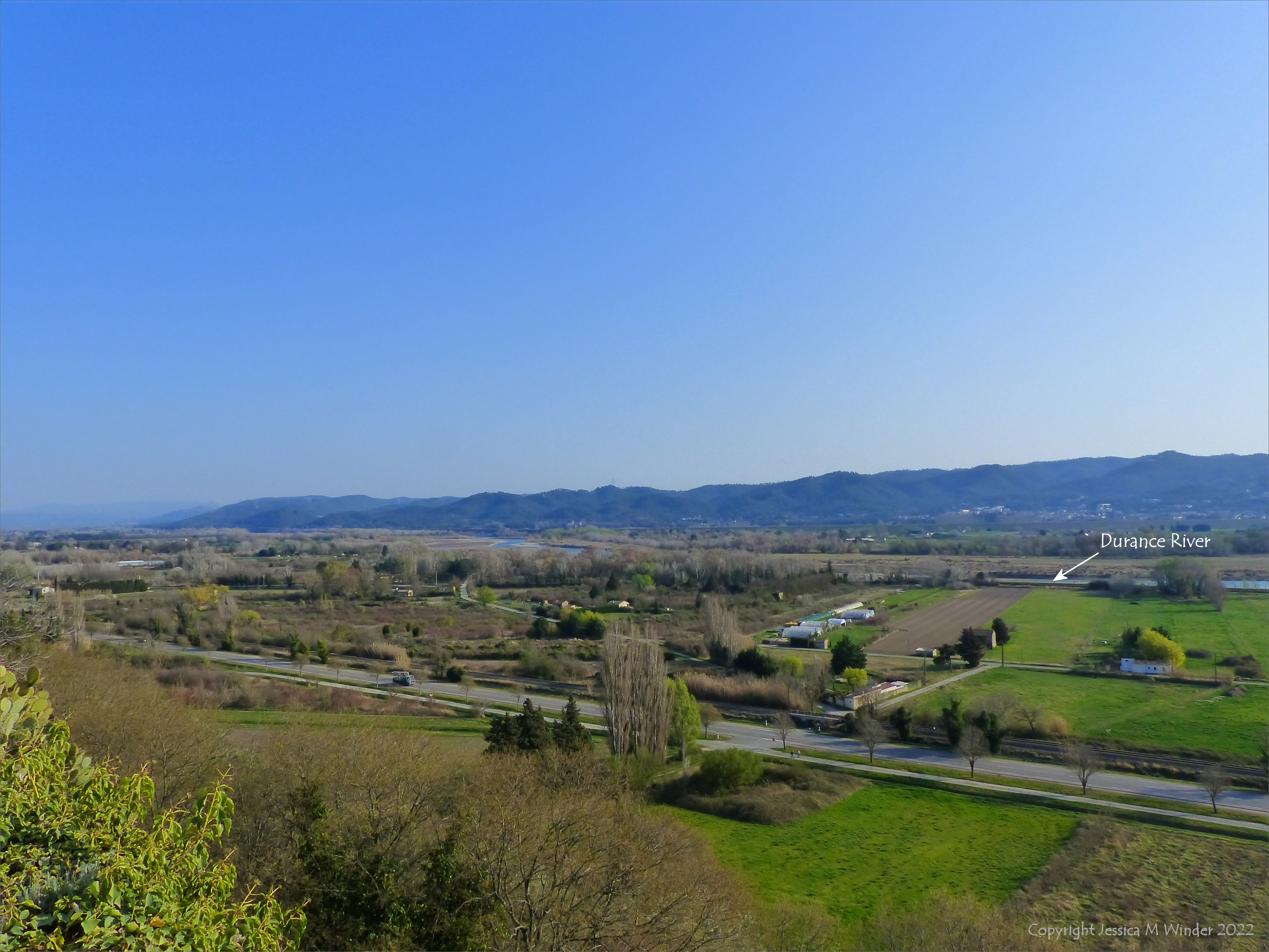 Green fertile river valley with hills on the horizon wnd blue sky in Provence, france