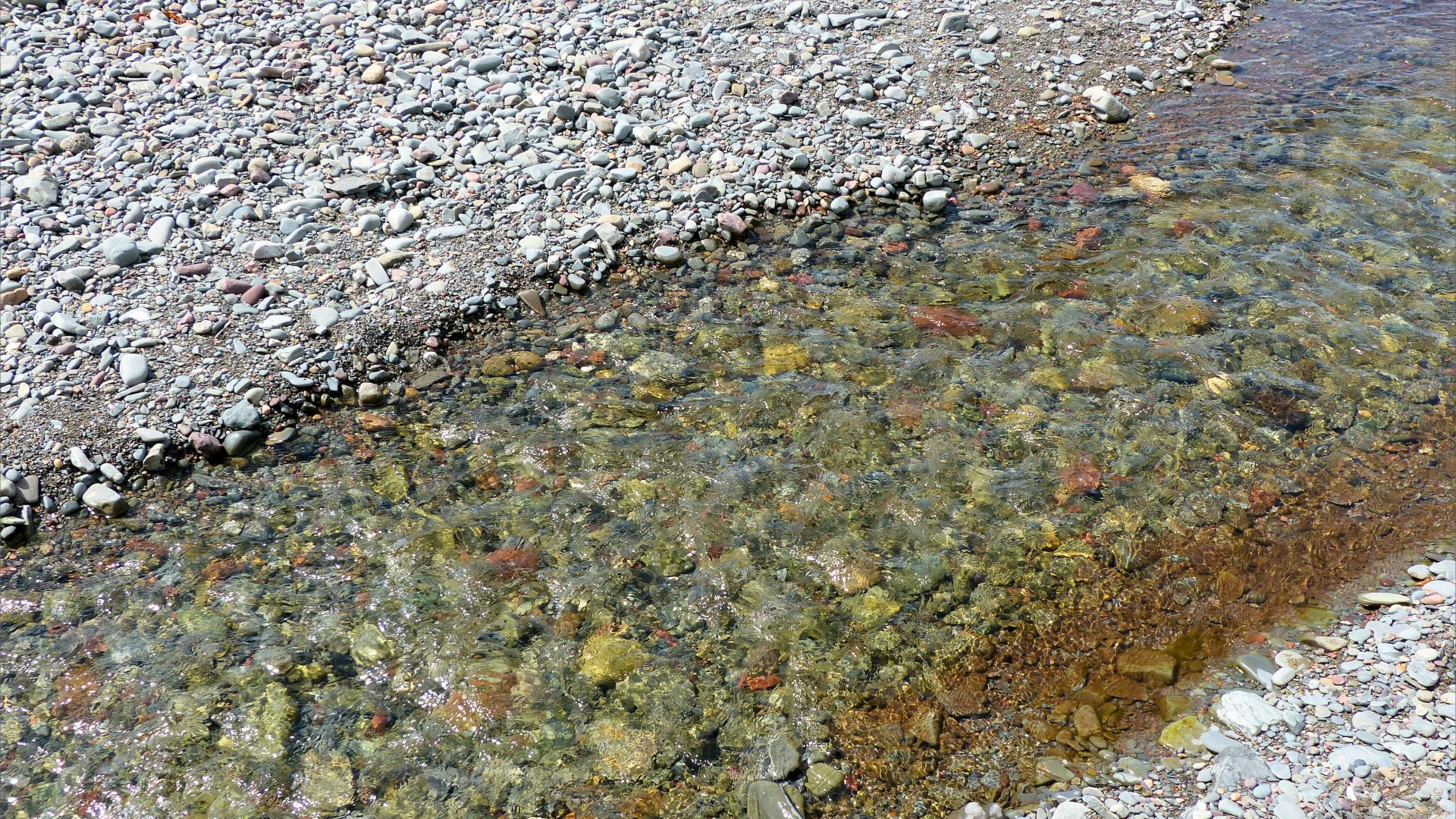 Clear stream flowing across a pebble beach