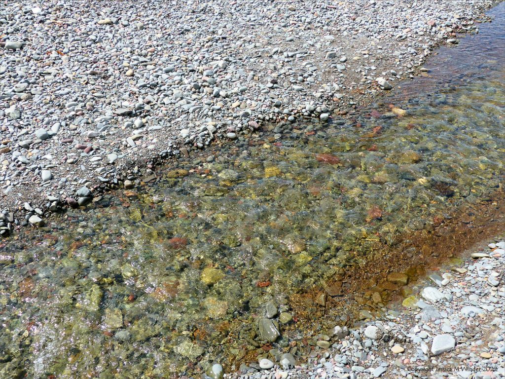 Clear stream flowing across a pebble beach