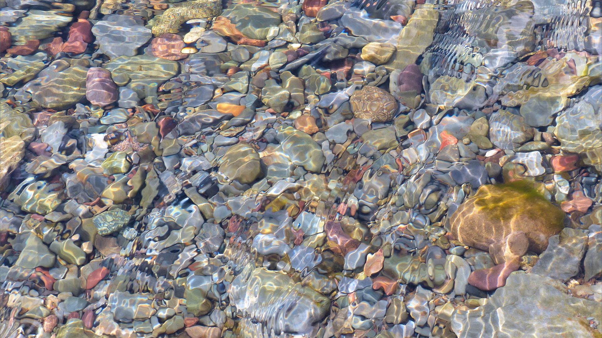 Coloured beach stones underwater in a stream