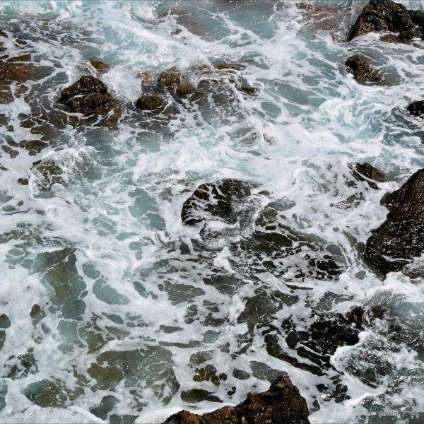 Texture of waves breaking on rocks with surf and sea foam