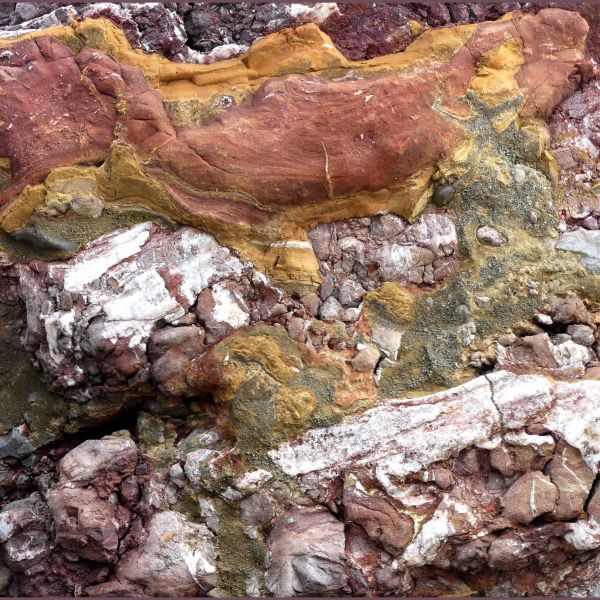 Natural pattern, colour and texture within a rock armour boulder at Seatown in Dorset showing a kind of multicoloured conglomerate of various rock types that are embedded within the main uniform sedimentary strata.