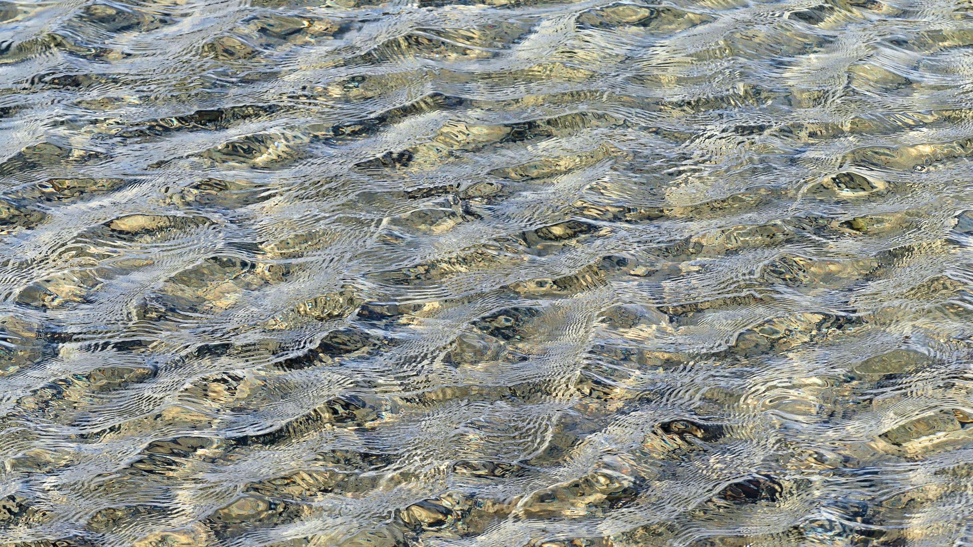 Natural abstract patterns of light reflected on wind-driven ripples in shallow water on the beach at Ogmore-by-Sea on the Glamorgan Heritage Coast in South Wales